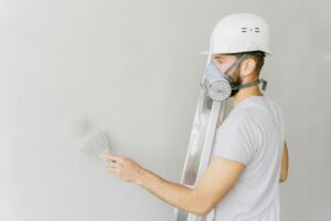 https://www.pexels.com/photo/man-in-white-t-shirt-wearing-white-gas-mask-using-flat-metal-spatula-on-the-wall-5493652/